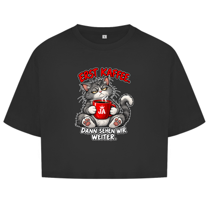 JA Erst Kaffee – Damen-Crop-Top in Schwarz, Vorderansicht, Frontdruck: Grimmige Katze mit roter Tasse: „Erst Kaffee. Dann sehen wir weiter.“
