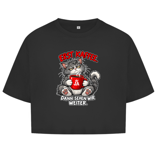 JA Erst Kaffee – Damen-Crop-Top in Schwarz, Vorderansicht, Frontdruck: Grimmige Katze mit roter Tasse: „Erst Kaffee. Dann sehen wir weiter.“