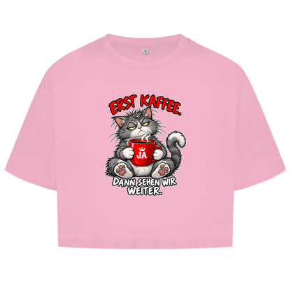 JA Erst Kaffee – Damen-Crop-Top in Hellrosa, Vorderansicht, Frontdruck: Grimmige Katze mit roter Tasse: „Erst Kaffee. Dann sehen wir weiter.“