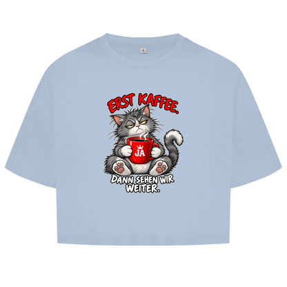 JA Erst Kaffee – Damen-Crop-Top in Himmelblau, Vorderansicht, Frontdruck: Grimmige Katze mit roter Tasse: „Erst Kaffee. Dann sehen wir weiter.“