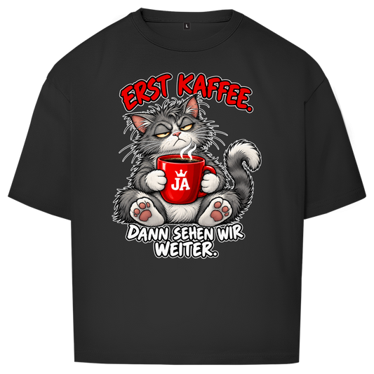 JA Erst Kaffee – Oversize-Shirt in Schwarz, Vorderansicht, Frontdruck: Grimmige Katze mit roter Tasse: „Erst Kaffee. Dann sehen wir weiter.“