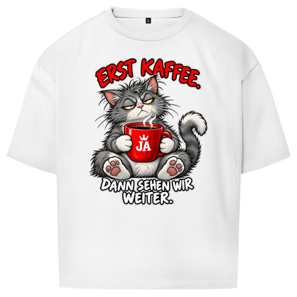 JA Erst Kaffee – Oversize-Shirt in Weiß, Vorderansicht, Frontdruck: Grimmige Katze mit roter Tasse: „Erst Kaffee. Dann sehen wir weiter.“