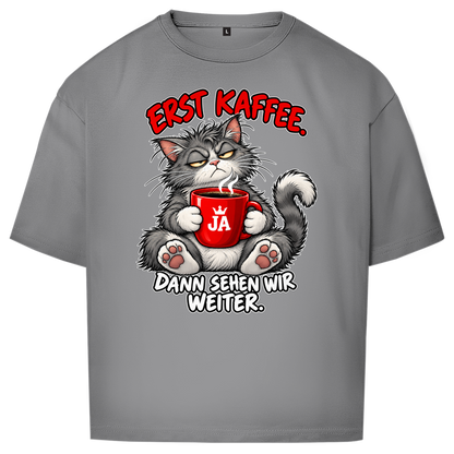 JA Erst Kaffee – Oversize-Shirt in Grau, Vorderansicht, Frontdruck: Grimmige Katze mit roter Tasse: „Erst Kaffee. Dann sehen wir weiter.“