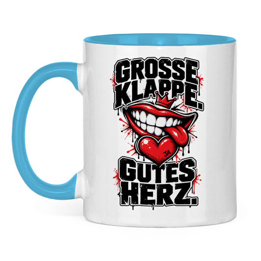 JA Große Klappe, gutes Herz – Tasse in Hellblau, Vorderansicht, Aufdruck: Markenspruch „Große Klappe. Gutes Herz.“ mit rotem Mund und Herz
