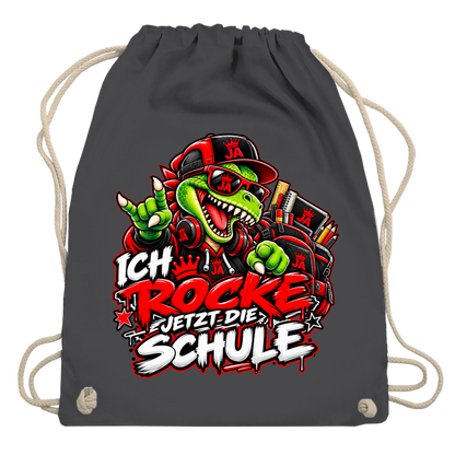 JA Schulstart Dino – Turnbeutel in Graphitgrau, Aufdruck: Dino mit Cap und Schulsachen: „Ich rocke jetzt die Schule“ zur Einschulung